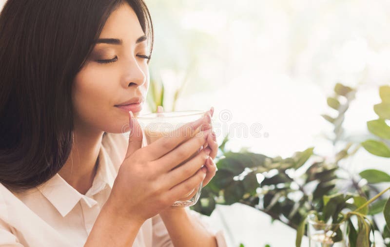 Attraktive asiatische Frau, die den Geruch des Morgenkaffees genießt lizenzfreies stockfoto Attraktive asiatische Frau, die den Geruch des Morgenkaffees genießt lizenzfreies stockfoto