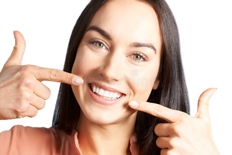 Attraktive Frau, die auf ihr Lächeln mit den perfekten weißen Zähnen zeigt