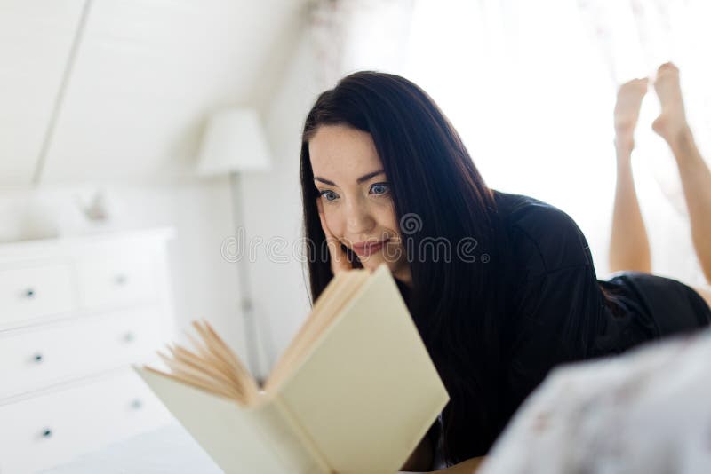 Attraktive Frau gekleidet im schwarzen sexy Sleepwear, der auf Bett legt stockbild Attraktive Frau gekleidet im schwarzen sexy Sleepwear, der auf Bett legt stockbild