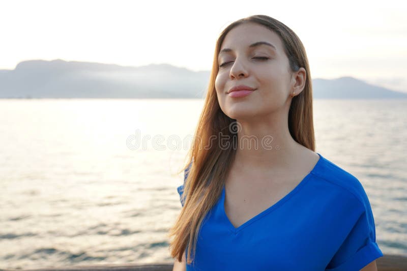 Attractive young woman breathing with closed eyes on sunset seascape. Attractive young woman breathing with closed eyes on sunset seascape.