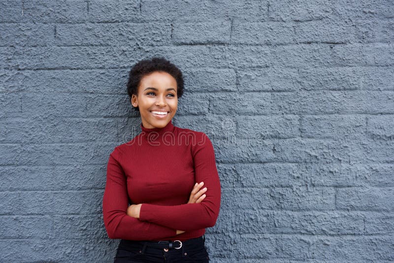 Attraktive lächelnde afrikanische Frau, die an der grauen Wand sich lehnt lizenzfreie stockfotos Attraktive lächelnde afrikanische Frau, die an der grauen Wand sich lehnt lizenzfreie stockfotos