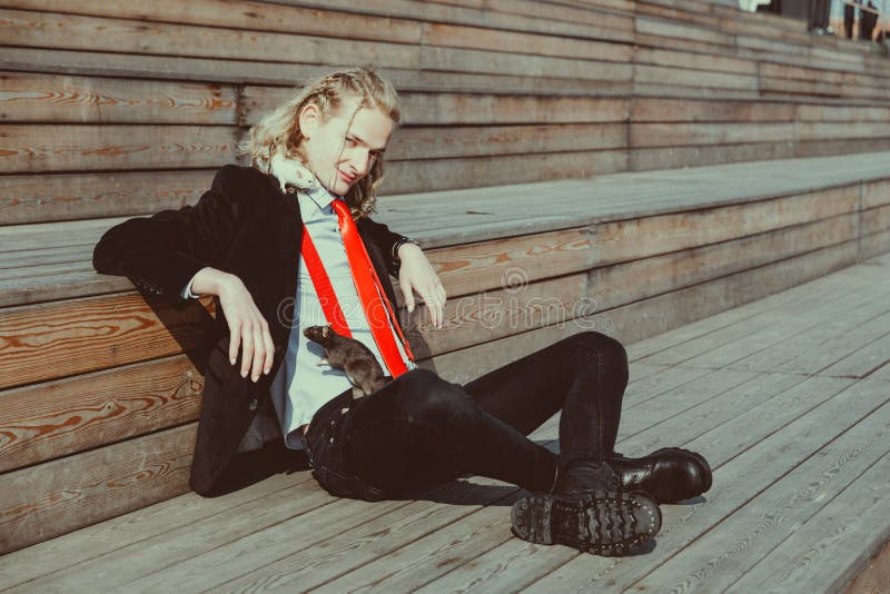Attractive young man with long blonde hair in a black suit and red tie, rats running around his body. Attractive young man with long blonde hair in a black suit and red tie, rats running around his body.