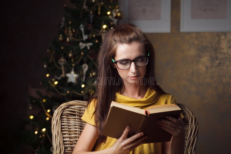Attraktives Buch der jungen Frau Lesenahe Weihnachtsbaum lizenzfreie stockfotografie Attraktives Buch der jungen Frau Lesenahe Weihnachtsbaum lizenzfreie stockfotografie