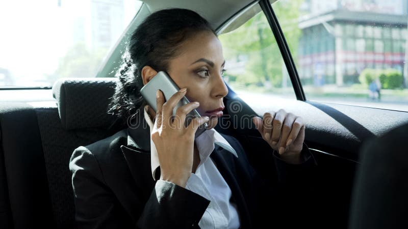 Attraktivt affärskvinnasammanträde i taxien som talar på telefonen, allvarlig konversation royaltyfria bilder Attraktivt affärskvinnasammanträde i taxien som talar på telefonen, allvarlig konversation royaltyfria bilder