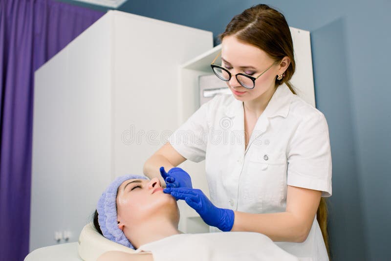 Au centre de beaut? Beau docteur de femme belle faisant le massage de visage au centre de beauté Fille de calme ayant le massage photographie stock Au centre de beaut? Beau docteur de femme belle faisant le massage de visage au centre de beauté Fille de calme ayant le massage photographie stock