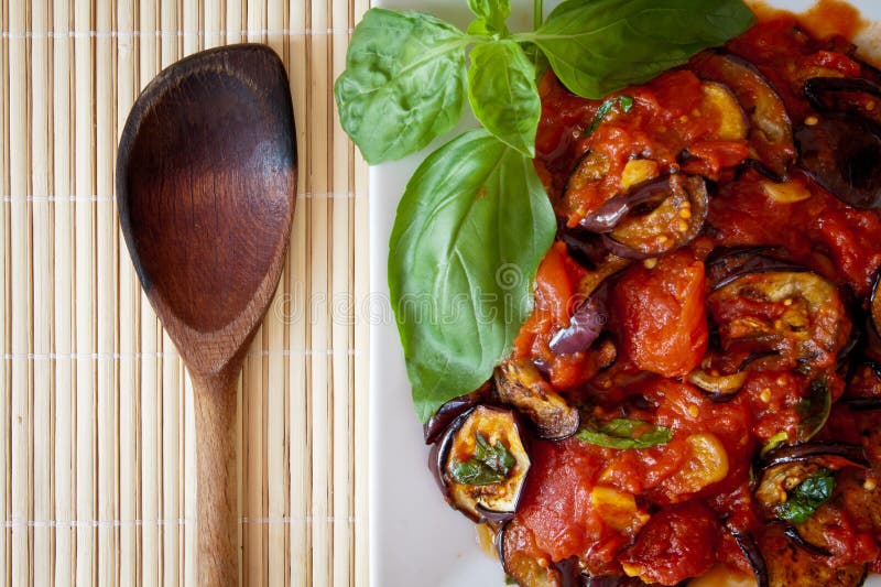 Aubergines in tomato sauce with wooden spoon