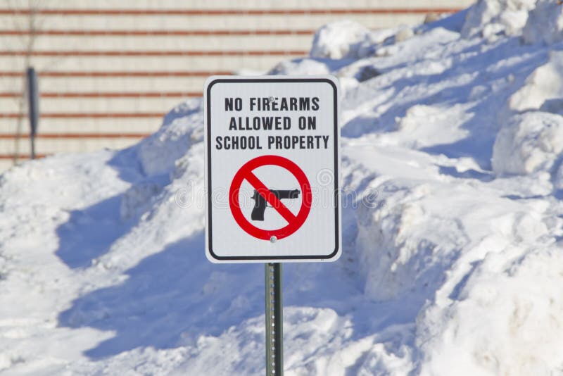 No Firearms Allowed on School Property Sign outside a school in the snow. No Firearms Allowed on School Property Sign outside a school in the snow.