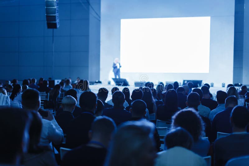 Audience listens to the lecturer at the conference hall. blue tinted photo