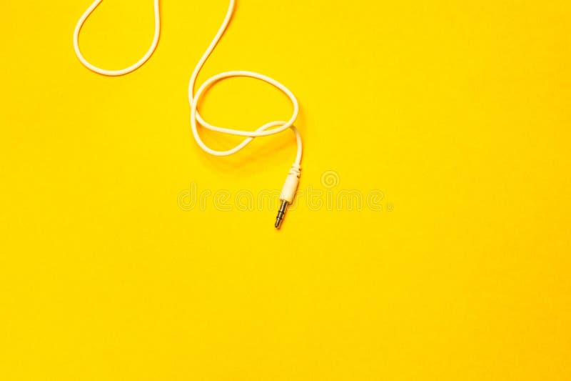 Audio jack with white cable on yellow background