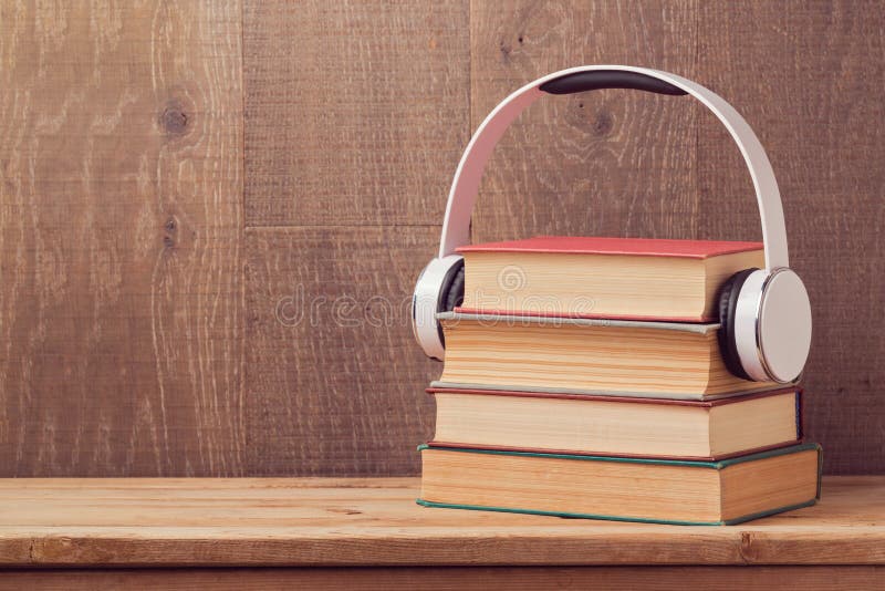 Audioboekenconcept met stapel oude boek en hoofdtelefoons op houten lijst