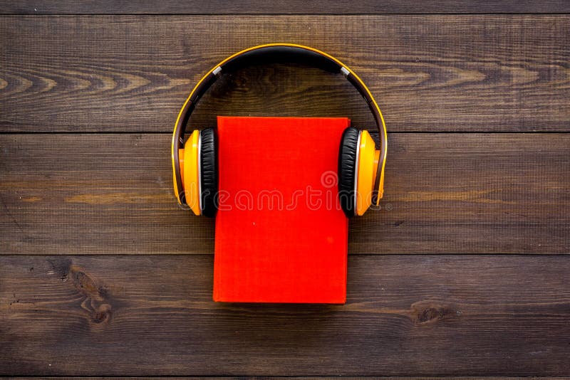 Audiobooksconcept De hoofdtelefoons zetten over boek met harde kaftboek met lege dekking op de donkere houten ruimte van het acht stock afbeelding Audiobooksconcept De hoofdtelefoons zetten over boek met harde kaftboek met lege dekking op de donkere houten ruimte van het acht stock afbeelding