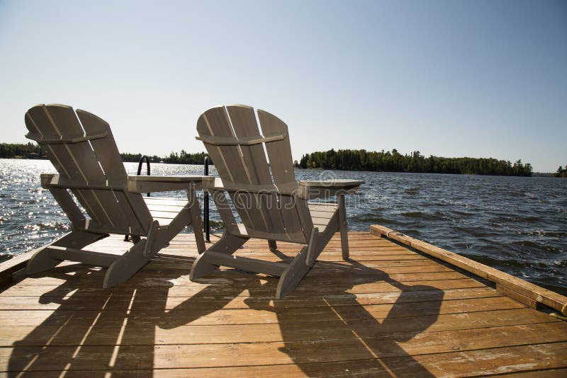 Kenora, Ontario, Canada on One of the most dramatic, mysterious and surprising lakes in the world. Lake of the Woods is a lake occupying parts of the Canadian provinces of Ontario and Manitoba and the U.S. state of Minnesota. It separates a small land area of Minnesota from the rest of the United States. Two arondak chairs. Kenora, Ontario, Canada on One of the most dramatic, mysterious and surprising lakes in the world. Lake of the Woods is a lake occupying parts of the Canadian provinces of Ontario and Manitoba and the U.S. state of Minnesota. It separates a small land area of Minnesota from the rest of the United States. Two arondak chairs.