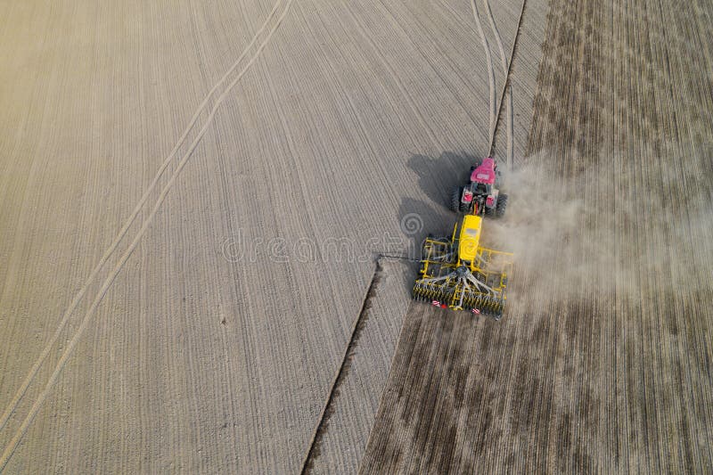 Tractor on a plowed field, top view. Agricultural field for planting vegetables. Tractor makes furrows on the field. Tractor on a plowed field, top view. Agricultural field for planting vegetables. Tractor makes furrows on the field.