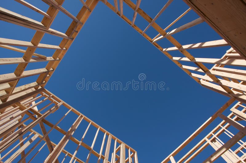 New residential construction home framing against a deep blue sky. New residential construction home framing against a deep blue sky.