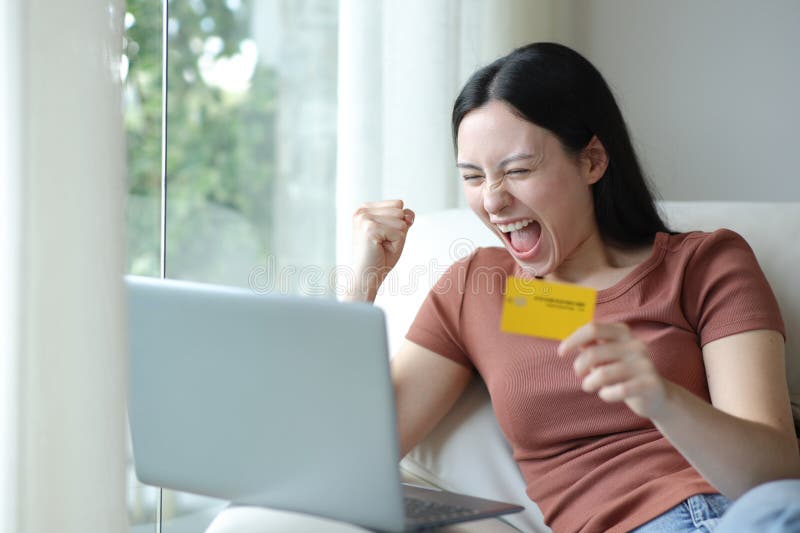 Aufgeregt asiatische Frau kauft online mit Laptop und Karte lizenzfreie stockfotografie