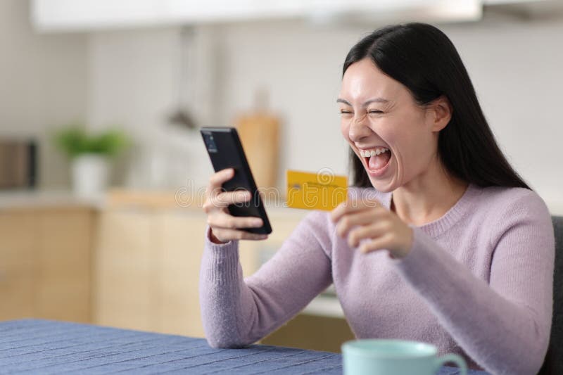 Aufgeregte asiatische Frau kauft online und feiert gute Nachrichten lizenzfreie stockbilder