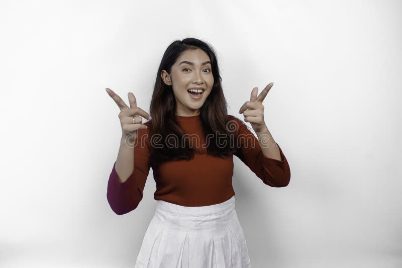 Aufgeregte asiatische Frau mit rotem Hemd, die auf den Kopierraum oben auf ihrer durch weißen Hintergrund isolierten.