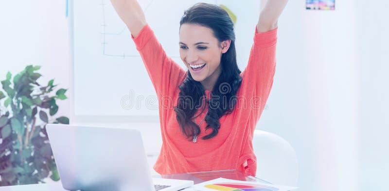 Aufgeregte Frau, die ihre Arme beim Arbeiten an ihrem Laptop anhebt stockbilder Aufgeregte Frau, die ihre Arme beim Arbeiten an ihrem Laptop anhebt stockbilder
