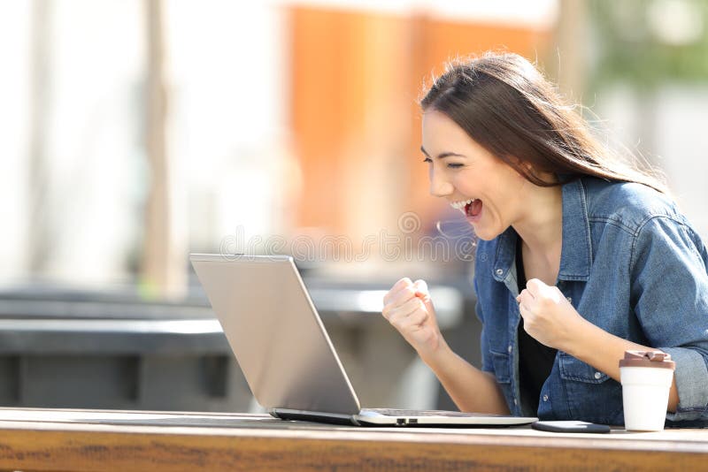 Aufgeregte Frau, die Laptopinhalt in einem Park überprüft