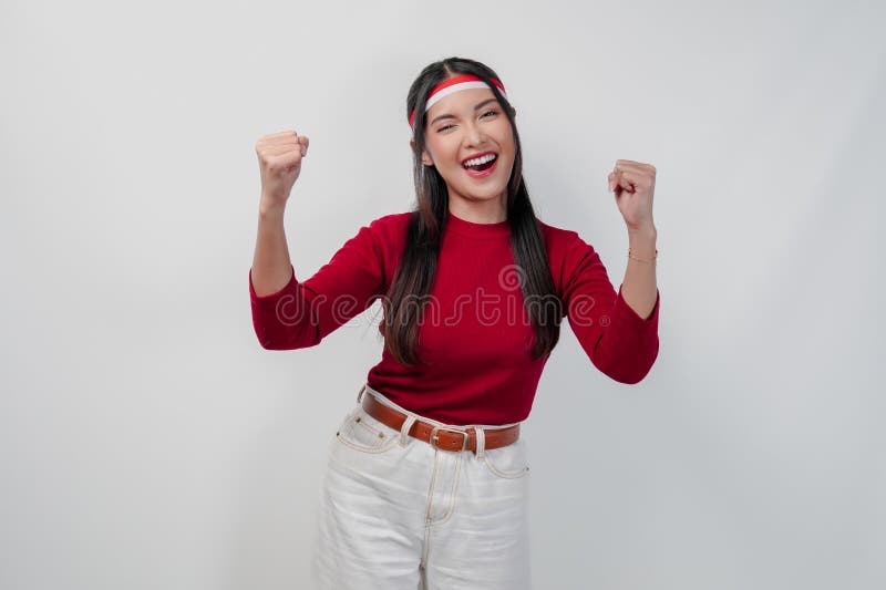 Aufgeregte junge Asiatin in einem roten Hemd und weiße Hosen heben ihre Hände. lizenzfreies stockbild