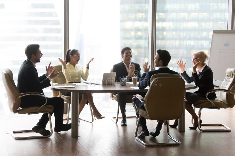 Excited multi ethnic corporate diverse team executive board sales group celebrate business success motivated by goal achievement happy about great result sitting at conference table in modern office. Excited multi ethnic corporate diverse team executive board sales group celebrate business success motivated by goal achievement happy about great result sitting at conference table in modern office.