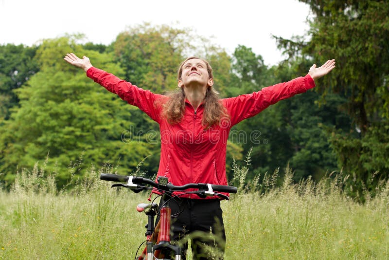 Excited happy woman cyclist standing on a nature with hands outstretched embracing vitality freedom. Outdoor. Excited happy woman cyclist standing on a nature with hands outstretched embracing vitality freedom. Outdoor