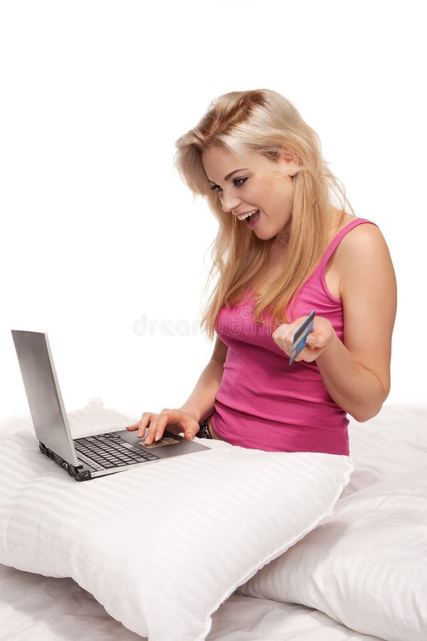 Excited attractive young blonde woman holding a credit card while doing online shopping reacting in amazement at finding exactly what she is looking for. Excited attractive young blonde woman holding a credit card while doing online shopping reacting in amazement at finding exactly what she is looking for