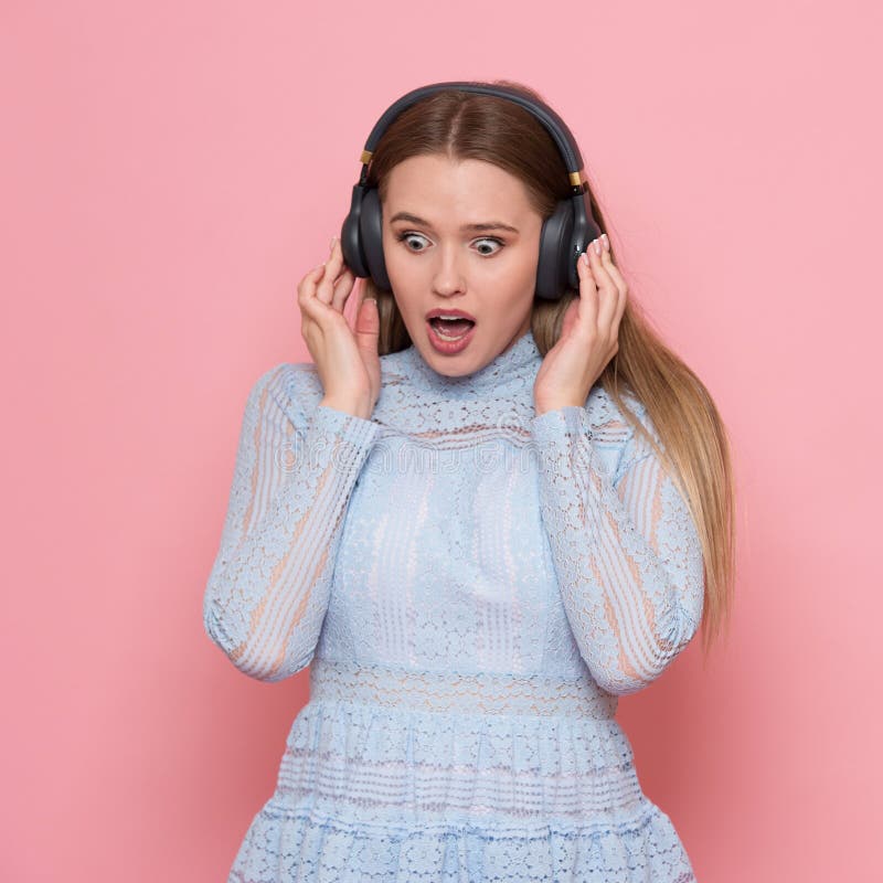 Aufgeregtes Frauentanzen und hören auf tragende Kopfhörer der Musik in der rosa Wand lizenzfreie stockfotografie Aufgeregtes Frauentanzen und hören auf tragende Kopfhörer der Musik in der rosa Wand lizenzfreie stockfotografie