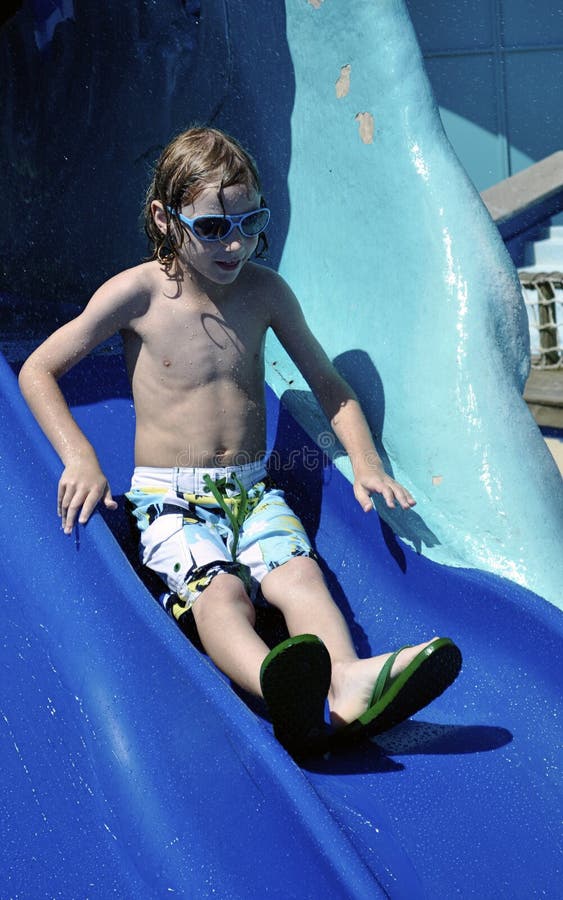 This is a picture of a very excited and happy little boy sliding down a water slide at a water park. This is a picture of a very excited and happy little boy sliding down a water slide at a water park.