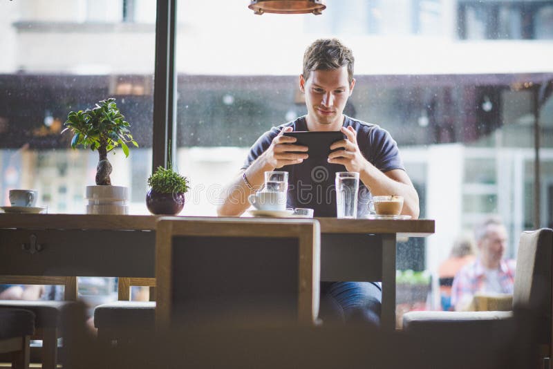 Aufpassende Tablette des jungen Mannes im Café lizenzfreies stockfoto Aufpassende Tablette des jungen Mannes im Café lizenzfreies stockfoto