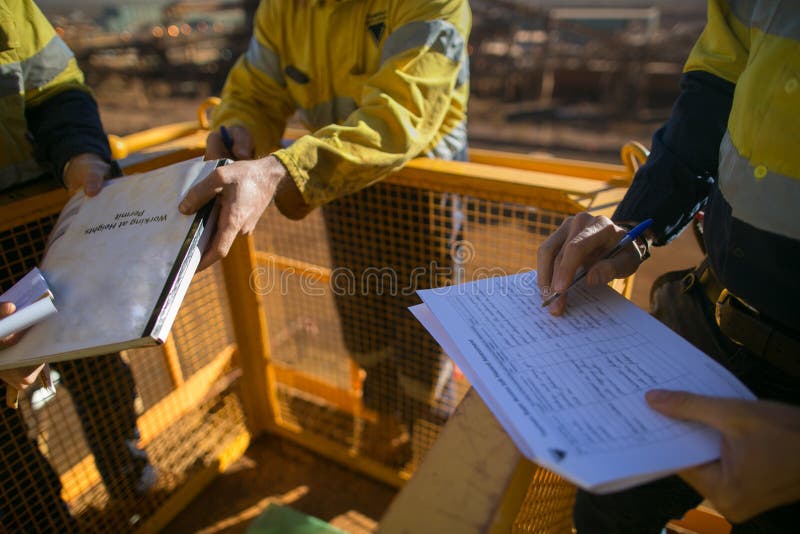 Miner supervisor checking before sigh of working at height permit JSA risk assessment on site prior to performing high risk work on construction site, Perth, Australia. Miner supervisor checking before sigh of working at height permit JSA risk assessment on site prior to performing high risk work on construction site, Perth, Australia