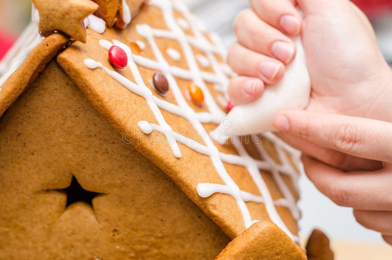 Auftragen der königlichen Vereisung auf Lebkuchenhaus lizenzfreies stockbild Auftragen der königlichen Vereisung auf Lebkuchenhaus lizenzfreies stockbild