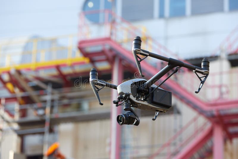 Augenschein in der Industrie. Kontrolle der hart Objekte aus der Luft in der Industrie. Datenzugriffsseiten-Ansicht. Ausstehend Schwarzes quadcopter mit starker Kamera gegen unscharfen Industriebau