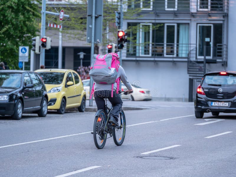 Augsburg Tyskland - Maj 5, 2019: Leveransman på cykeln med matasken i purpurfärgad färg royaltyfria foton Augsburg Tyskland - Maj 5, 2019: Leveransman på cykeln med matasken i purpurfärgad färg royaltyfria foton