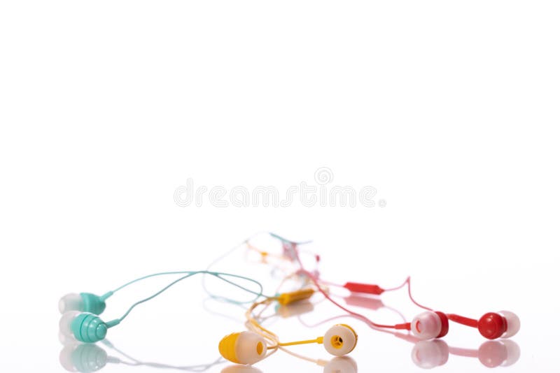 Auricolari verdi gialli e rossi isolati su fondo bianco Ascoltare musica fotografie stock