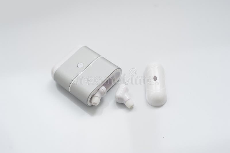 Auriculares inalámbricos blancos con la caja de carga aislada en el fondo blanco Nueva tecnología para los corredores: auricular imagenes de archivo Auriculares inalámbricos blancos con la caja de carga aislada en el fondo blanco Nueva tecnología para los corredores: auricular imagenes de archivo