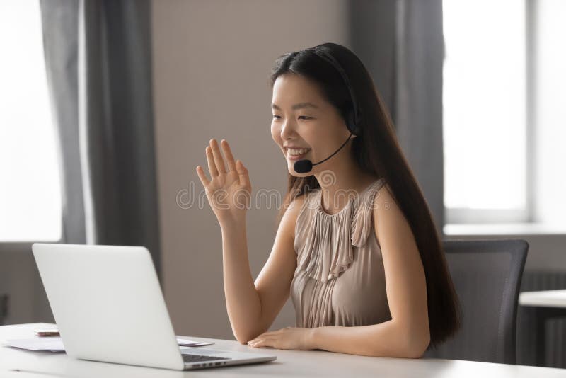 Auriculares inalámbricos que llevan sonrientes de la empresaria asiática que agitan haciendo la charla video