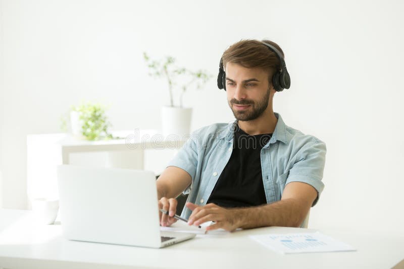 Auriculares que llevan concentrados del trabajador que escuchan webinar en l fotografía de archivo Auriculares que llevan concentrados del trabajador que escuchan webinar en l fotografía de archivo