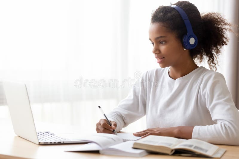 Auriculares que llevan de la muchacha adolescente afroamericana que aprenden lengua en línea