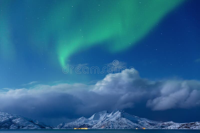 Aurora borealis, Tronso, Norway.  Green northern lights over Fjord And Mountains,  Night winter landscape with Starry sky and polar lights, aurora and snowy mountain in Background. Aurora borealis, Tronso, Norway.  Green northern lights over Fjord And Mountains,  Night winter landscape with Starry sky and polar lights, aurora and snowy mountain in Background