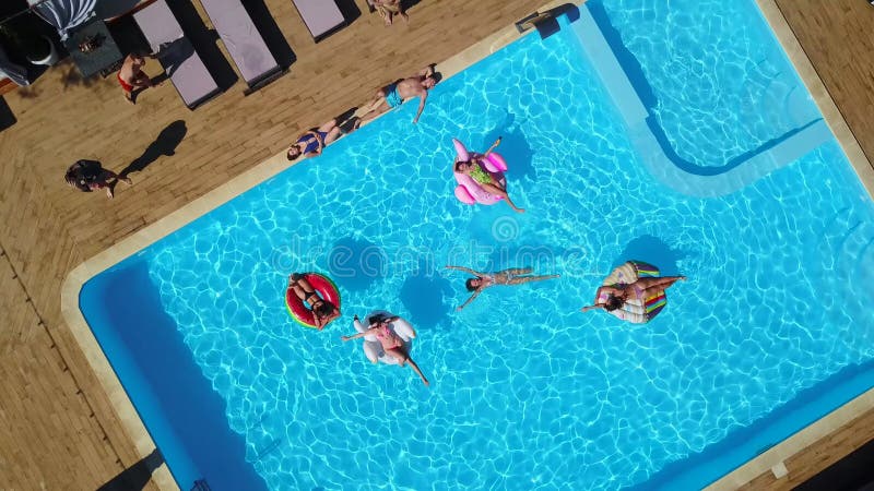 Aus der Luft. Freunde, die im Swimmingpool mit aufblasbarer Flamingoschwanmatratze kühlen. glückliche Jugendliche baden auf dem Sc