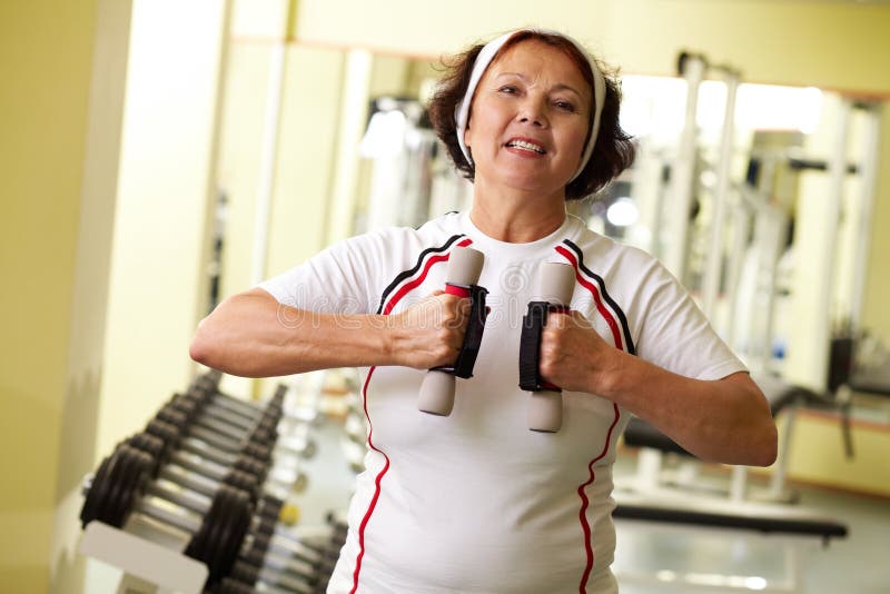 Persistent elder woman with dumbbells keeping fit. Persistent elder woman with dumbbells keeping fit