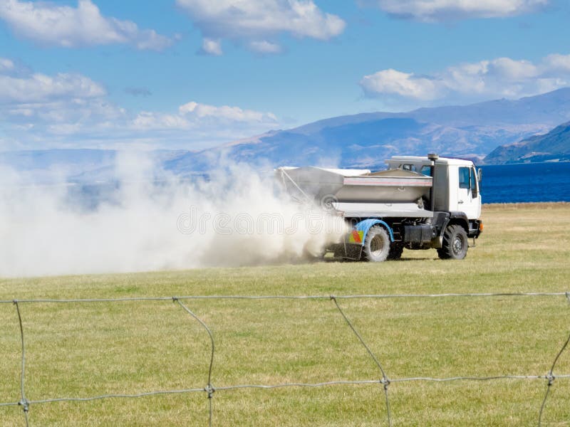 Truck spreading fertilizer on pasture meadow creating an enormous white dust cloud of rock phosphate and potash. Truck spreading fertilizer on pasture meadow creating an enormous white dust cloud of rock phosphate and potash