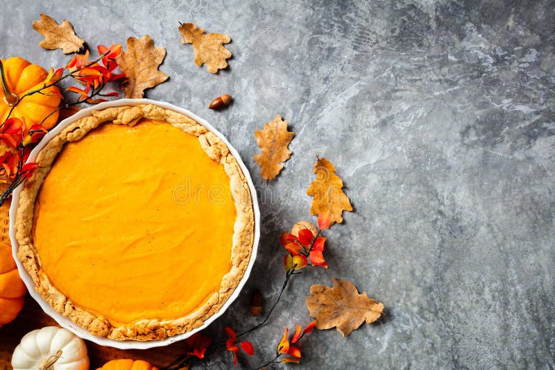 Aussicht auf einen gemütlichen Kürbiskuchen im Herbst, umgeben von farbenfrohen Herbstblättern und kleinen Kürbissen stockbilder