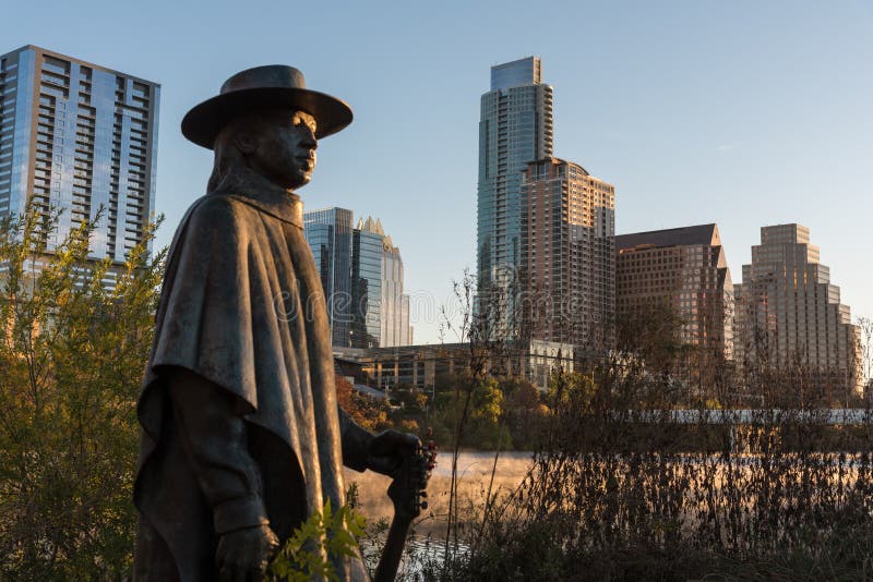 Stevie Ray Vaughan statue in Austin Texas at dawn with building in background. Stevie Ray Vaughan statue in Austin Texas at dawn with building in background