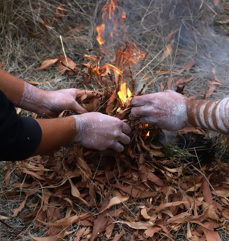 Australian Aboriginal Ceremony, man s hand with green branches and flame, start a fire for a ritual rite at a community event