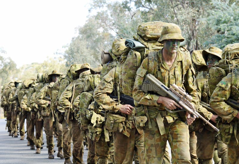 Australian army soldiers marching road to base in camouflage bush war tactics training