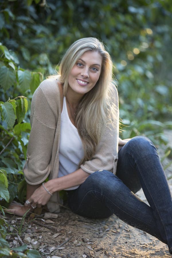 Australian Beauty with Long Blond Hair Sits by a Tree. Stock Photo