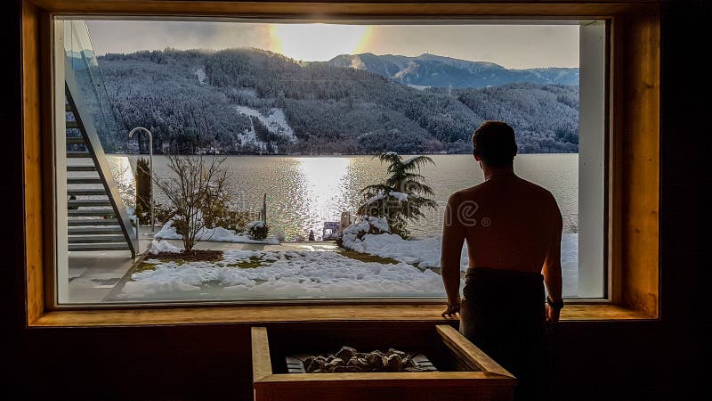 Austria - A young man in an alpine sauna wirh the view on the lake an the mountans stock photos Austria - A young man in an alpine sauna wirh the view on the lake an the mountans stock photos