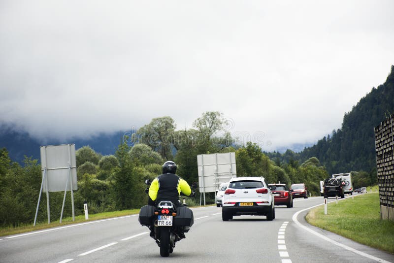 Austriaco y gente de los viajeros que conduce el coche y que monta la moto en el camino foto de archivo libre de regalías